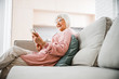 © Yakobchuk Olena - Joyful senior lady sitting on couch and using mobile phone