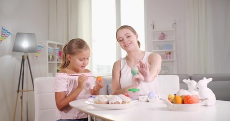 Sticker - Happy mother and daughter painting eggs for Easter celebration at home