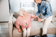 © Yakobchuk Olena - Young lady helping grandmother to get up from couch
