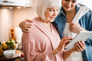 Wall Mural - Grandmother and adult granddaughter using digital tablet