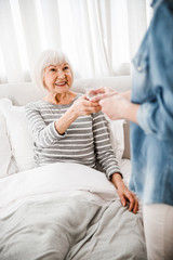 Young lady giving glass of water to elderly woman