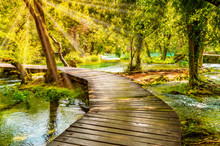 Wooden Footpath Over River In Forest Of Krka National Park, Croatia. Beautiful Scene With Trees, Water And Sunrays.
