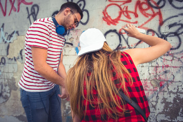 Urban couple writing graffiti on the wall