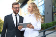 © ty - Office colleagues talking outdoors near the office building, discussing new project, holding digital tablet.