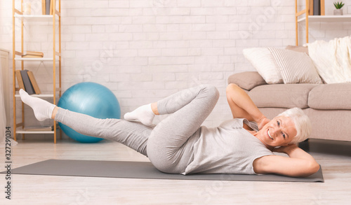 Fotomural Sporty senior woman doing abs exercise on floor at home