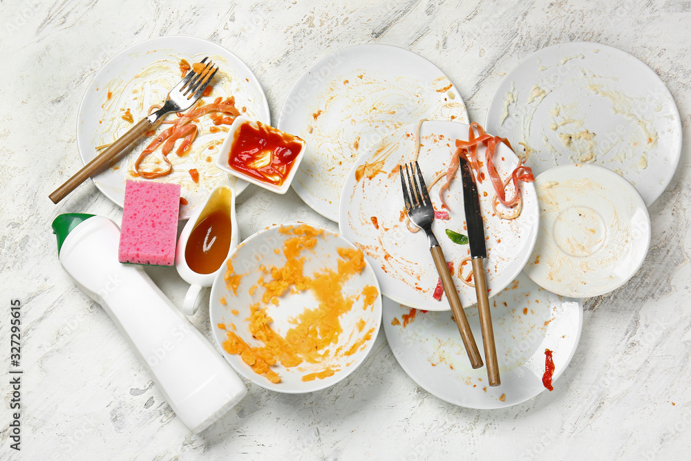 Dirty empty tableware and detergent on light background