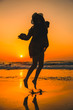 © unai - Lifestyle, a young woman jumping for joy on a sunset at the beach