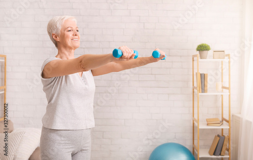 Fotografía Senior woman exercising with dumbbells at home