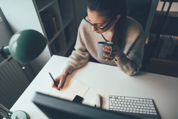 young woman working on computer at her home office