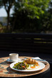 breakfast with croissant, sunny side up eggs, salad and coffee served on a round table in the garden