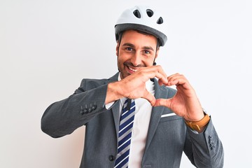 Wall Mural - Young handsome business man wearing suit and tie and bike helmet over isolated background smiling in love showing heart symbol and shape with hands. Romantic concept.