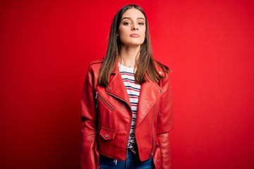 Wall Mural - Young beautiful brunette woman wearing casual jacket standing over red background Relaxed with serious expression on face. Simple and natural looking at the camera.