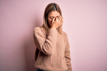 Sticker - Young beautiful blonde woman wearing winter wool sweater over pink isolated background tired rubbing nose and eyes feeling fatigue and headache. Stress and frustration concept.