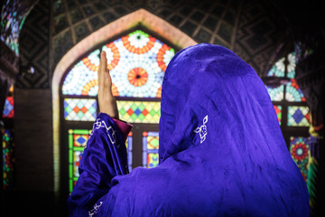 Wall Mural - Muslim woman praying for Allah muslim god at room near window. Hands of muslim woman on the carpet praying in traditional wearing clothes, Woman in Hijab, Carpet of Kaaba, Selective focus, toned