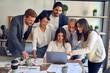 © Krakenimages.com - Group of business workers smiling happy and confident. One of them sitting and partners standing around. Working together with smile on face looking at the laptop at the office