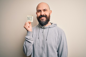 Wall Mural - Handsome bald man with beard holding reminder paper with negative message with a happy face standing and smiling with a confident smile showing teeth