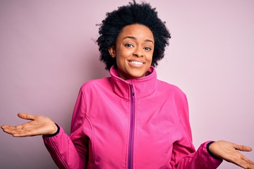 Sticker - Young African American afro sportswoman with curly hair wearing sportswear doin sport clueless and confused expression with arms and hands raised. Doubt concept.