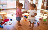 Adorable toddlers playing around lots of toys at kindergarten