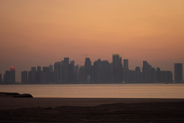 Wall Mural - Vibrant Skyline of Doha at dramatick sunset as seen from the opposite side of the capital city bay 
