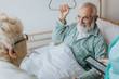 © Photographee.eu - Senior patient gets up from the hospital bed by helping himself with a special handle