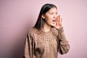 Sticker - Young beautiful asian woman wearing fashion and elegant sweater over pink solated background shouting and screaming loud to side with hand on mouth. Communication concept.