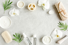 Spa Treatment Concept. Natural/Organic Spa Cosmetics Products, Sea Salt, Massage Brush, Tropic Palm Leaves On Gray Marble Table From Above. Spa Background With A Space For A Text, Flat Lay, Top View