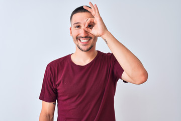 Poster - Young handsome man standing over isolated background doing ok gesture with hand smiling, eye looking through fingers with happy face.