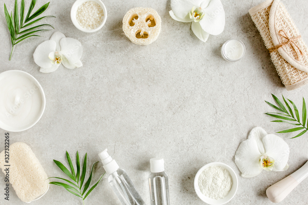 Spa treatment concept. Natural/Organic spa cosmetics products, sea salt, massage brush, tropic palm leaves on gray marble table from above. Spa background with a space for a text, flat lay, top view - obrazy, fototapety, plakaty 