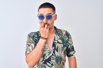 Wall Mural - Young handsome man wearing Hawaiian sumer shirt and blue sunglasses over isolated background looking stressed and nervous with hands on mouth biting nails. Anxiety problem.