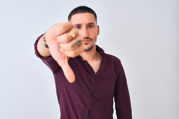 Poster - Young handsome business man standing over isolated background looking unhappy and angry showing rejection and negative with thumbs down gesture. Bad expression.