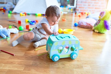 Adorable toddler playing around lots of toys at kindergarten