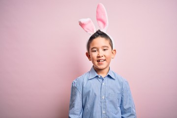 Sticker - Young little boy kid wearing easter bunny ears over isolated pink background with a happy and cool smile on face. Lucky person.