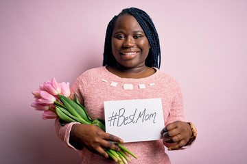 Sticker - Plus size african american woman holding best mom message and tulips on mothers day with a happy face standing and smiling with a confident smile showing teeth