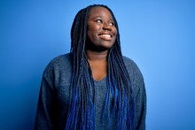African American Plus Size Woman With Braids Wearing Casual Sweater Over Blue Background Looking Away To Side With Smile On Face, Natural Expression. Laughing Confident.