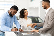 © Prostock-studio - Couple Shaking Hands With Salesman In Cars Selling Center