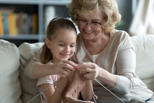 Happy Senior Grandmother And Little Granddaughter Knit Together