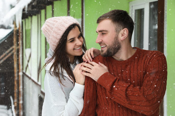 Wall Mural - Lovely couple wearing warm sweaters outdoors on snowy day. Winter season