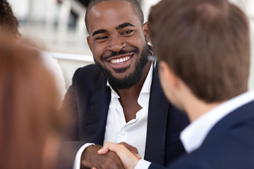 Sticker - Smiling african american man handshaking white businessman at meeting negotiation.