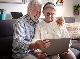 Aged web surfer. Two senior people share the laptop looking and planning a new travel. White hair - couple in retirement