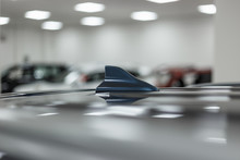 Close-up GPS Antenna Shark Fin Shape On A Roof Of Car For Radio Navigation System. Antenna Shark Fin On Blurry Background. Car Detail. Classic Blue Color