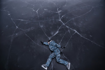 Wall Mural - a man in ice skates lies on the transparent ice of the lake, view from above, aerial photography