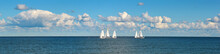 A Group Of Sailboats Or Yachts, A Race On A Sea Or Ocean. Beautiful Sky With Clouds.