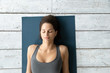 © fizkes - Above view young woman lying on mat during Shavasana pose