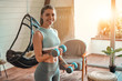 © Valerii Apetroaiei - Determined woman losing weight at home and exercising with dumbbells. Sport and recreation concept. Beautiful woman in sportswear with blue dumbbells in her hands.
