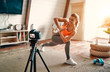 © Valerii Apetroaiei - Athletic woman blogger in sportswear shoots video on camera as she does exercises at home in the living room. Sport and recreation concept. Healthy lifestyle.