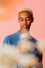 Portrait of  a beautiful young woman with trendy fresh makeup of pink lips and eyeliner holding carnation flower