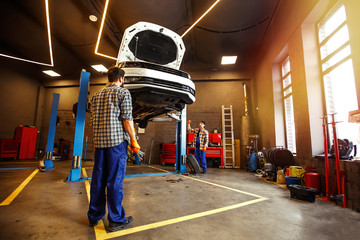 two specialists in uniform repairing car together in garage