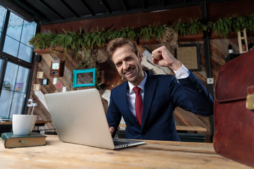 Wall Mural - young businessman working on laptop and celebrating victory