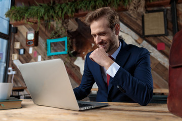 Wall Mural - happy businessman working on laptop and smiling