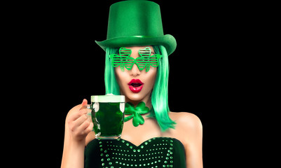 St. Patrick's Day leprechaun laughing model girl holding Green Beer pint, isolated on black background.  Shamrock leaf accessories. Celebrating Patrick Day pub party. Surprised young woman in costume